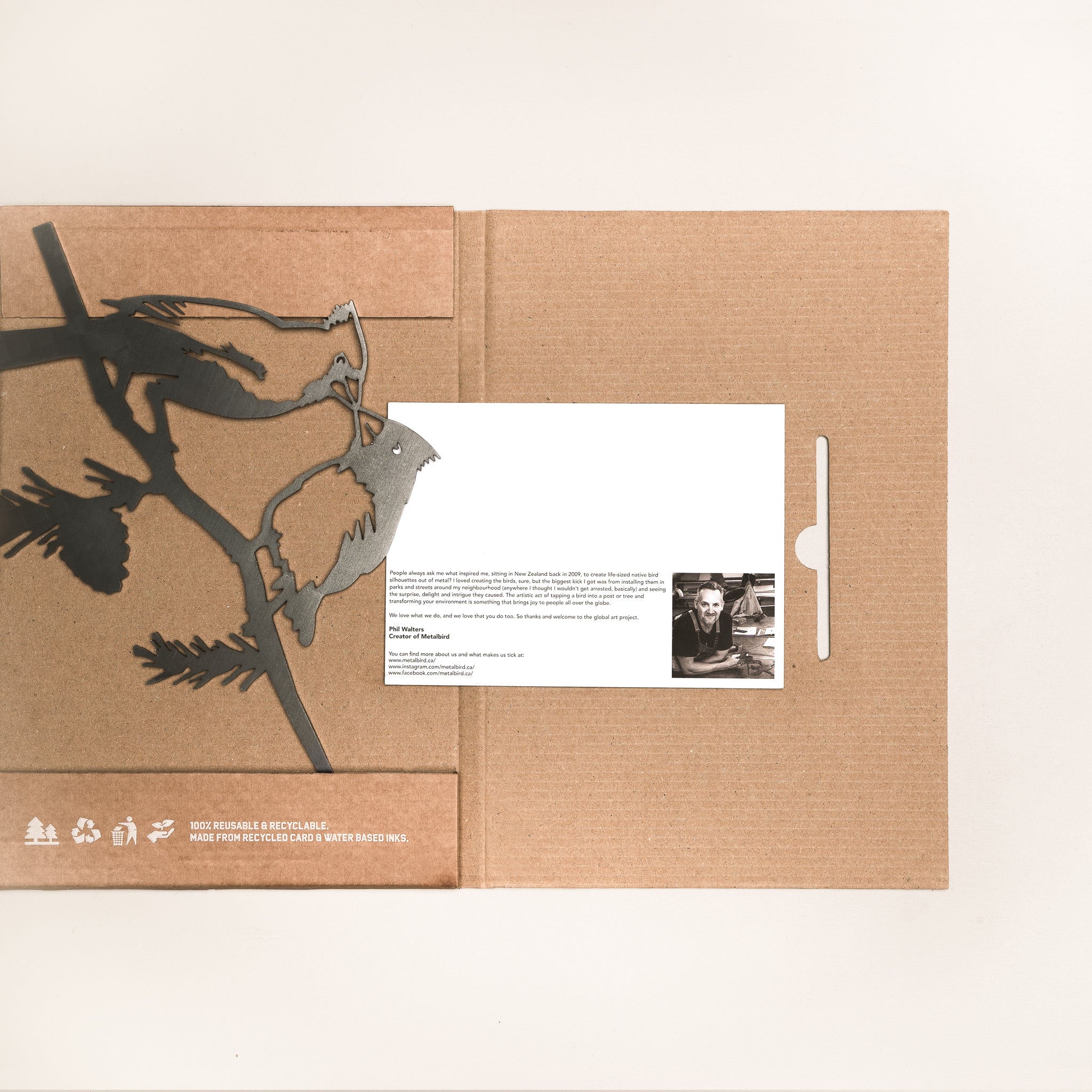 A brown cardboard folder with a cutout bird motif, inspired by Metal Bird Garden Art - Cardinal, Hummingbird, Owl - Gift For Bird Lovers, holds a white card with text and a black-and-white photo, displayed on a plain white background.