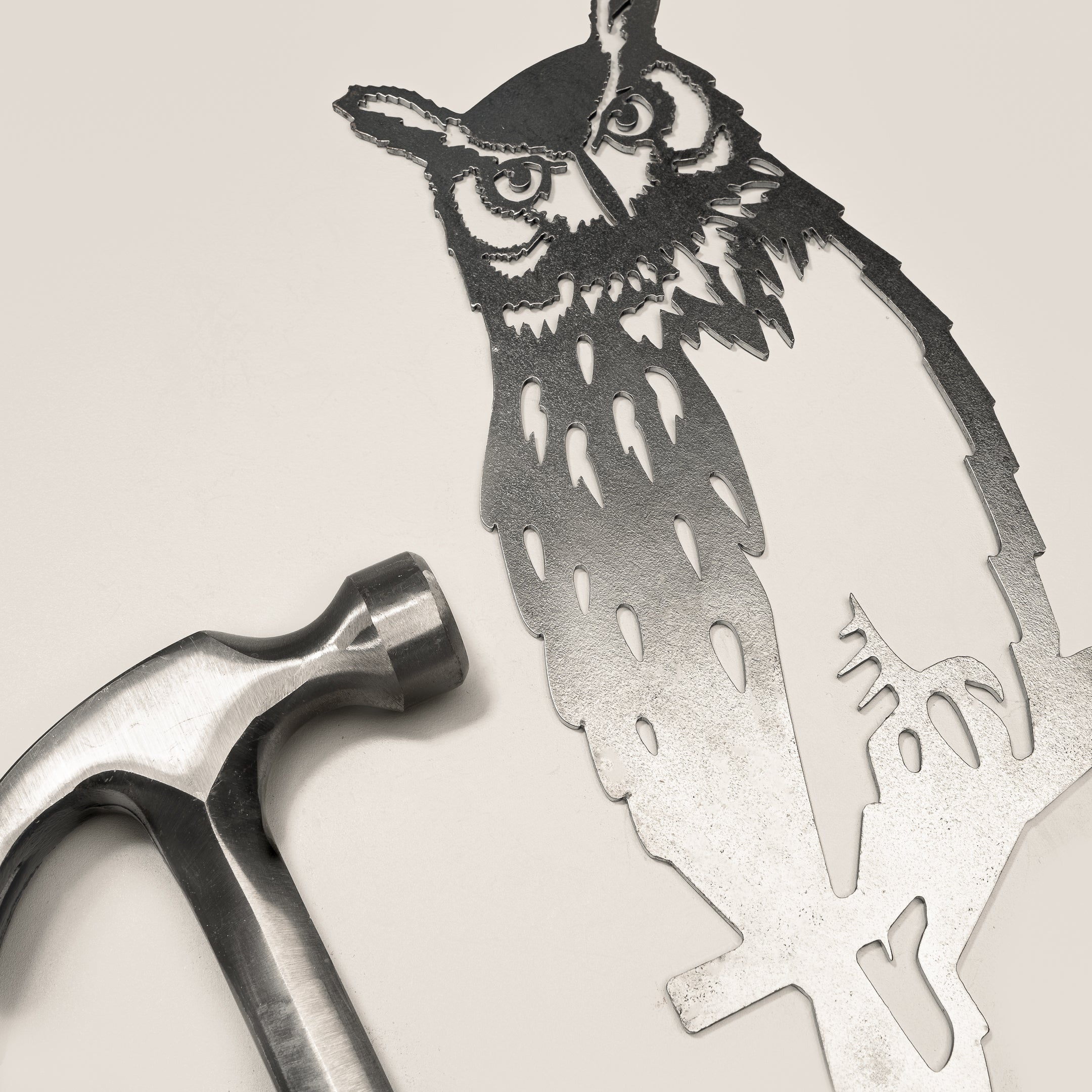 Raw Corten steel Great Horned Owl sculpture next to a hammer, ready for easy installation as striking garden art or memorial decor