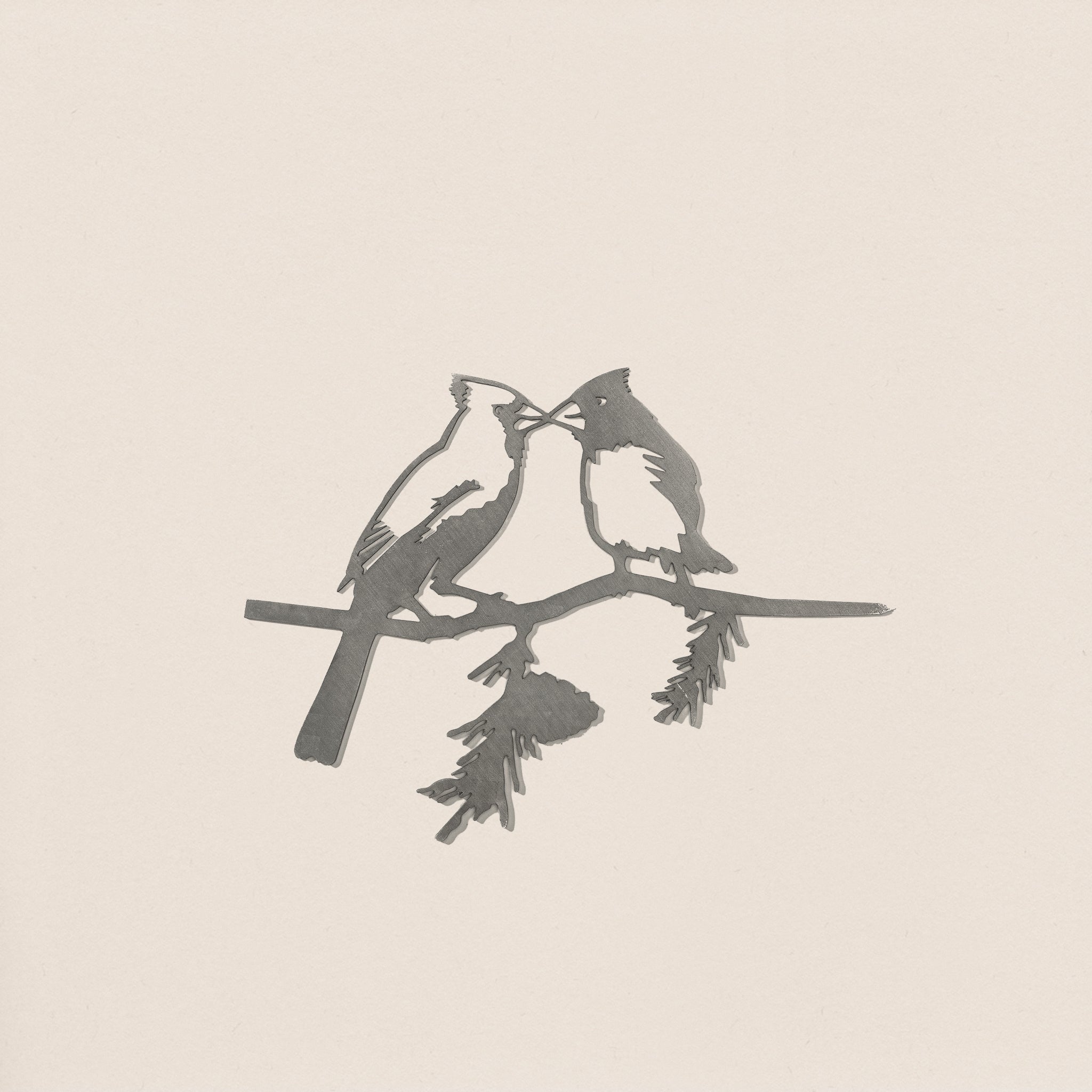Kissing Cardinals features a minimalist, monochrome illustration of two cardinals perched closely on a pine branch, their beaks nearly touching—ideal inspiration for elegant metal or corten steel yard art.