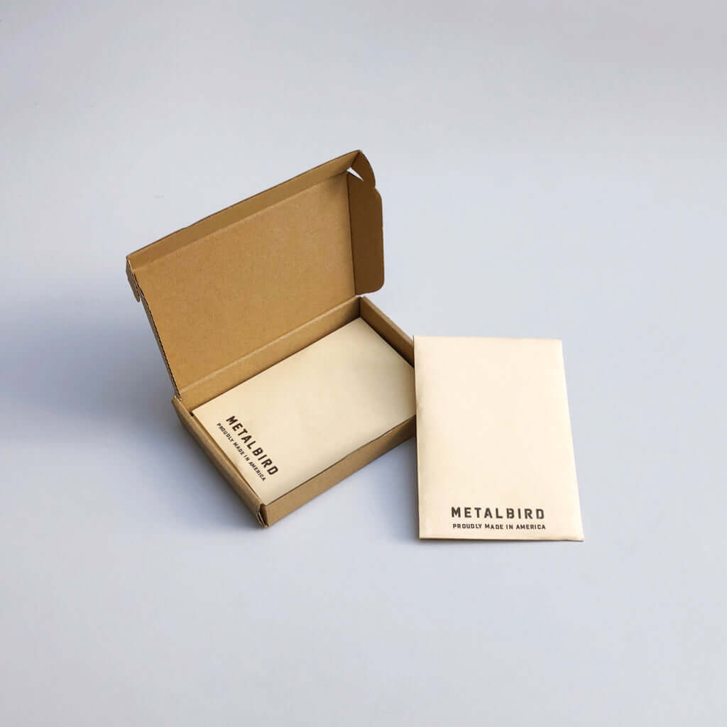 The Baby Bird Bundle features a small open cardboard box with two envelopes marked METALBIRD PRODUCT MADE IN AMERICA—ideal as a gift for anyone who loves unique silhouette yard art, all set on a light gray surface.