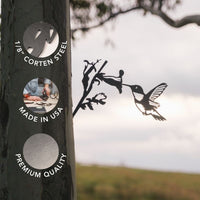 A metal silhouette named "Hummingbird," crafted from 1/8 inch Corten steel, features a Ruby-Throated Hummingbird and flower attached to a tree, creating charming garden decor. Overlays read: "1/8 Corten Steel," "Made in USA," and "Premium Quality." A blurred landscape and sky appear in the background.