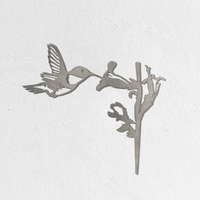 The Metalbird Seconds - Hummingbird is a premium metallic yard art silhouette showing a hummingbird feeding from a flower, displayed against a plain white textured wall.