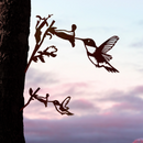 The Hummingbird Mom & Mini Set features two corten steel hummingbirds drinking from flowers on a tree trunk, with a pastel sunset sky—perfect as a hummingbird garden gift.