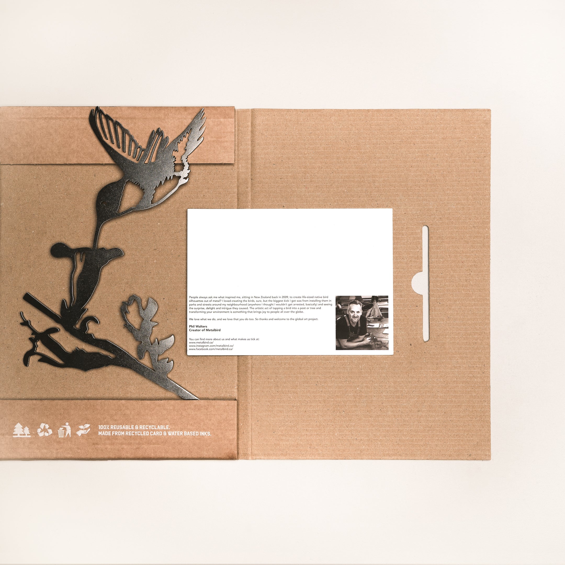 The Hummingbird Mom & Mini Set features a brown cardboard folder with a Corten steel hummingbird and branch design, plus a postcard with photo and text. Eco-friendly and recyclable—an ideal gift for hummingbird garden lovers.