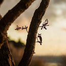 Silhouettes of a cardinal, hummingbird, and owl from the Mini Metal Bird Garden Art set perch on branches against a soft sunset sky—an ideal gift for bird lovers.