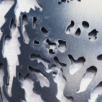 A close-up of the Metalbird Seconds - Blue Jay & Chick shows its intricate cut-out design in corten steel, with a smooth, slightly reflective surface and a textured background beneath.