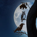 Corten steel crow, owl, and bat silhouettes perch on a tree branch under a full moon. Spooky garden art gift.