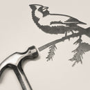 Raw Corten steel cardinal sculpture beside a hammer, showing simple setup for nature-inspired decor and outdoor garden art.