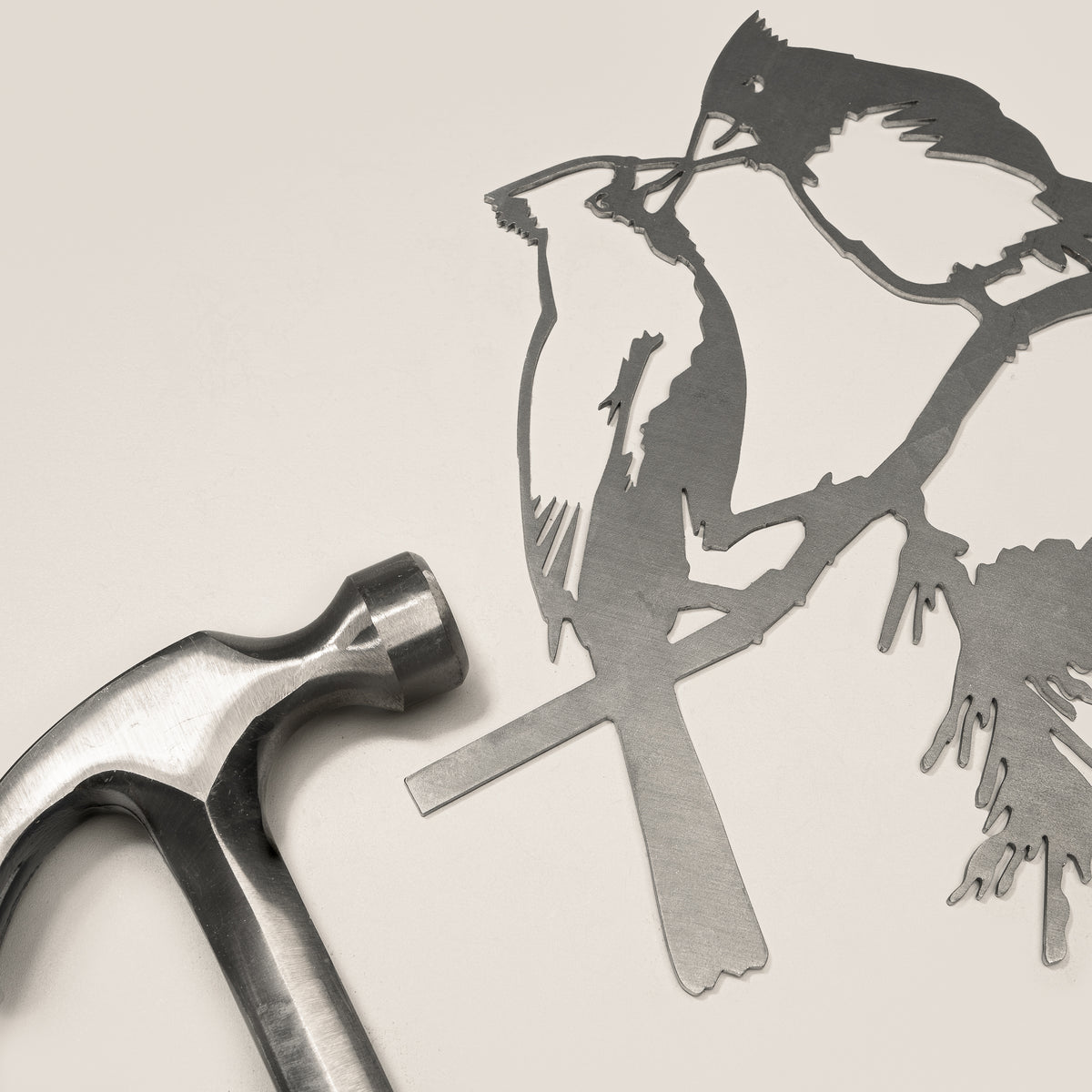 Kissing Cardinals steel silhouette beside a hammer.
