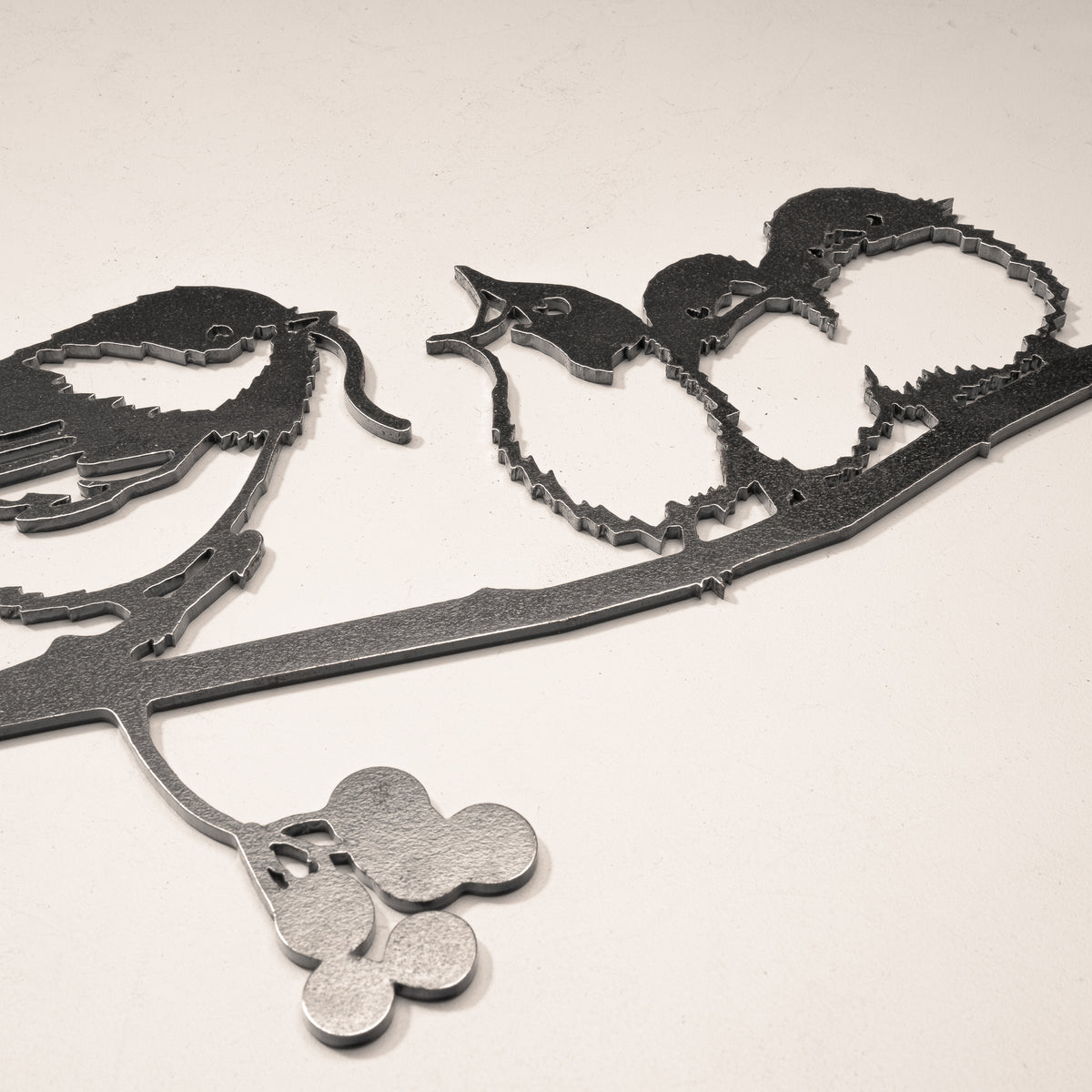 Close-up of the chickadee and three chick cutouts on a steel branch.