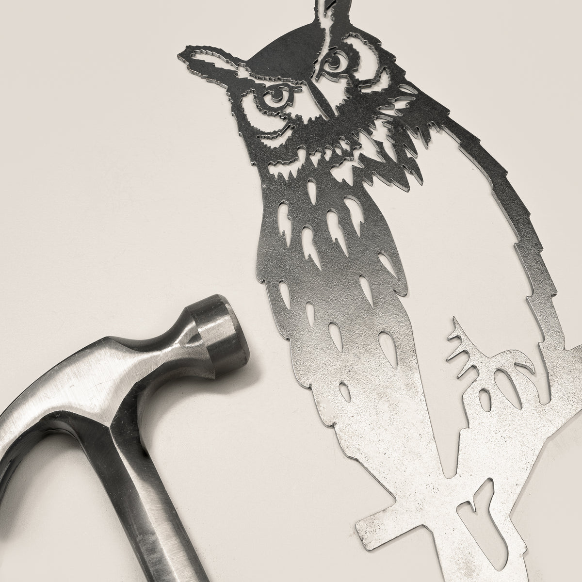Great Horned Owl steel silhouette beside a hammer.