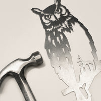 Raw Corten steel Great Horned Owl sculpture next to a hammer, ready for easy installation as striking garden art or memorial decor
