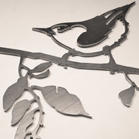 The "Nuthatch" metal wall art features a nuthatch perched on a leafy branch against a light background—a perfect tribute to backyard birds.