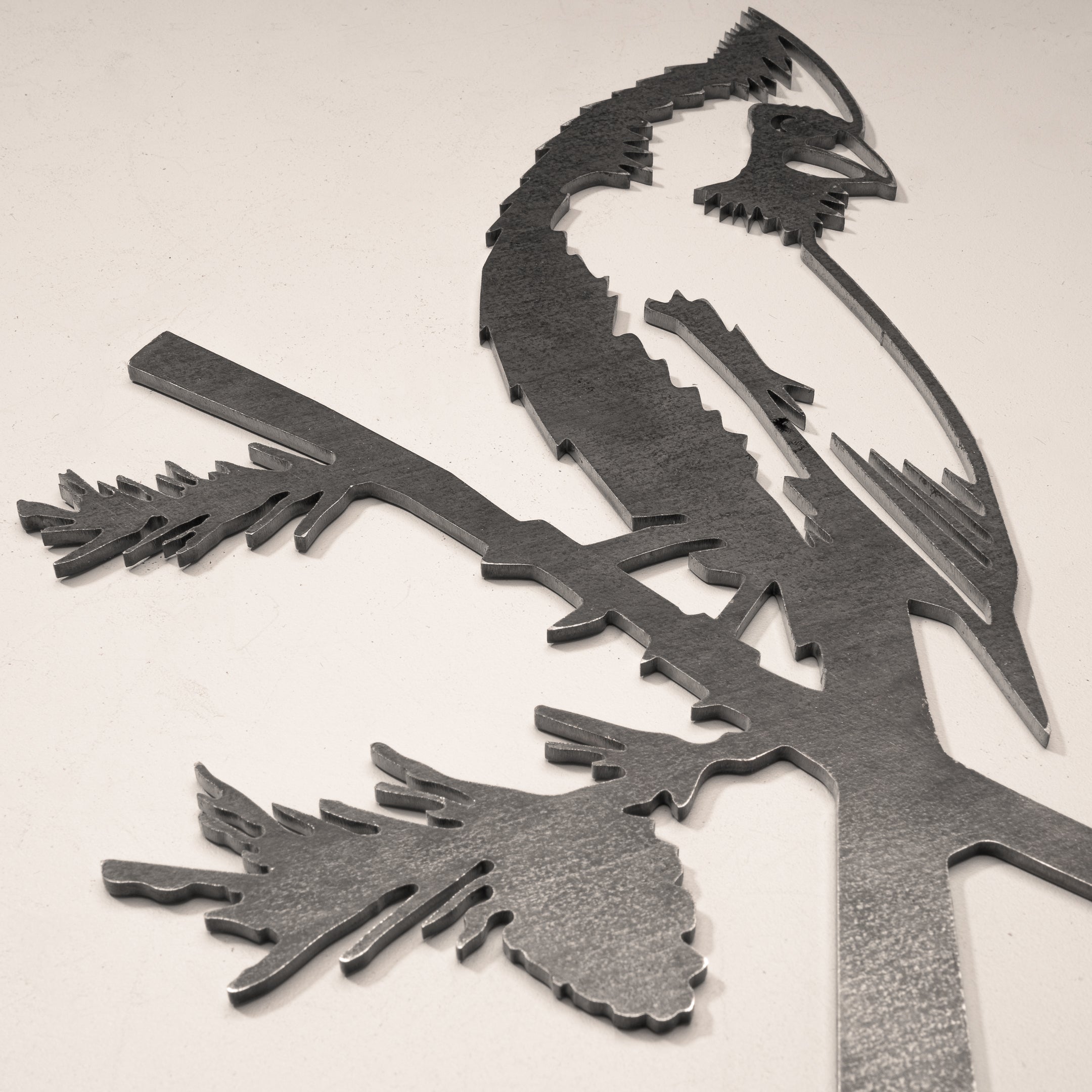 Close-up of raw Corten steel cardinal silhouette with pine detail, a handcrafted outdoor bird sculpture for garden or memorial use.