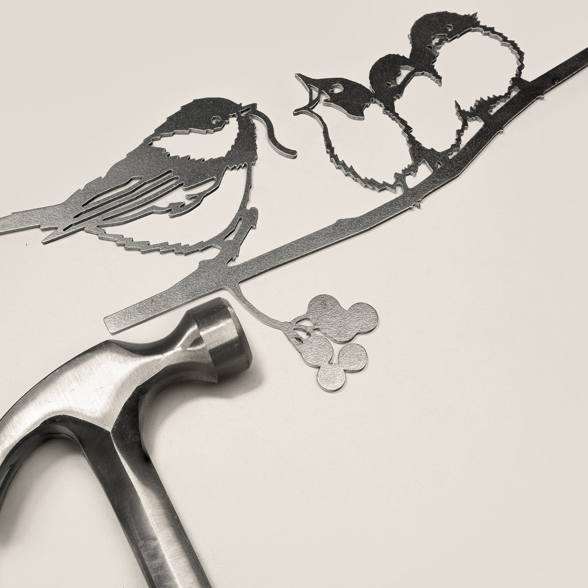Chickadee & Chicks steel silhouette beside a hammer.