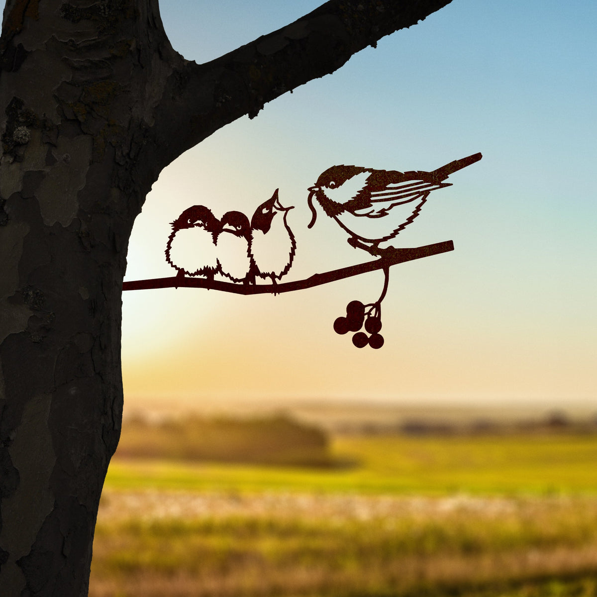 Chickadee and three chicks in steel on a shared branch beside a tree trunk.