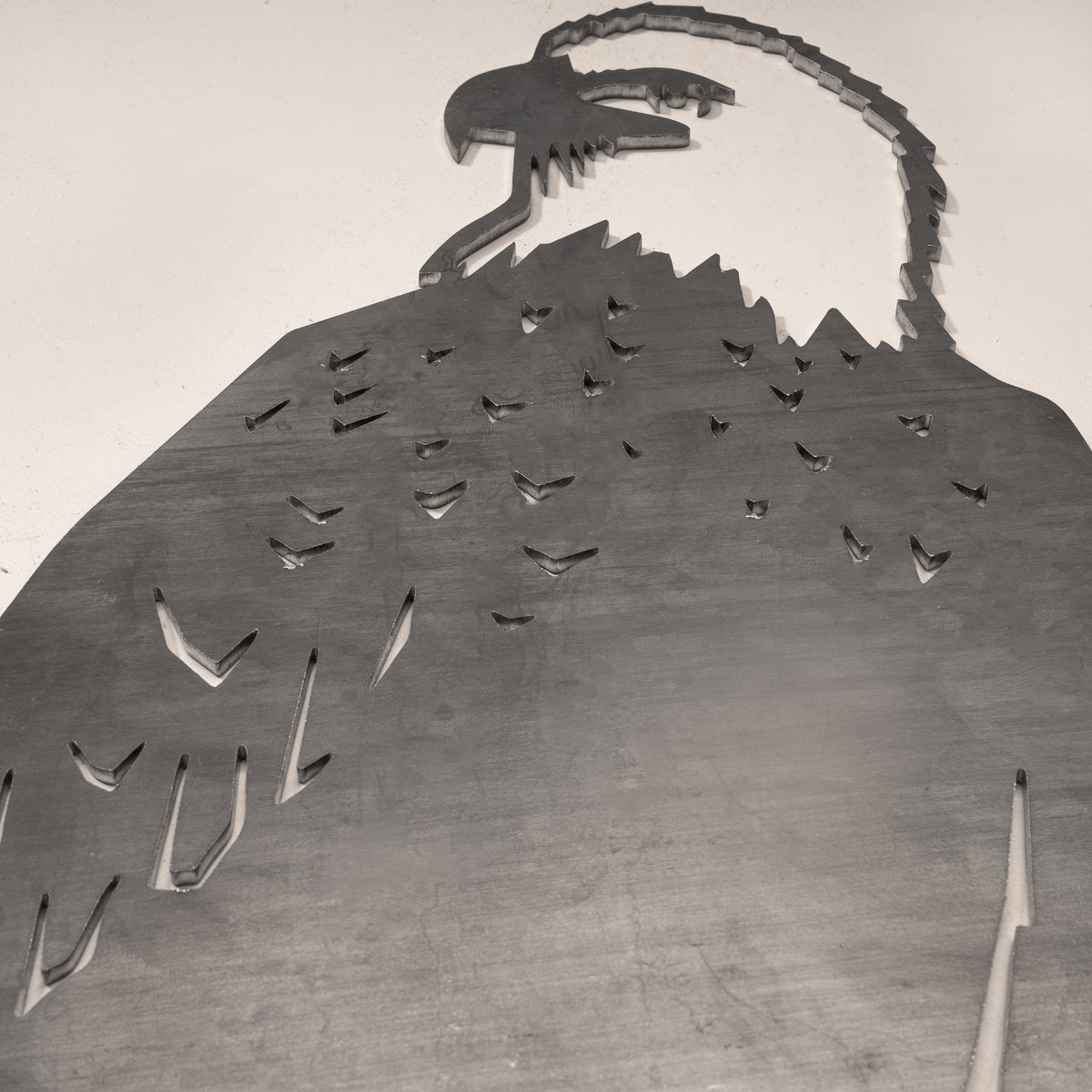 Close-up of the Bald Eagle head and feather cutouts in gray steel.