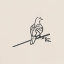 A simple line drawing of the Turtle Dove ornament with detailed wings, perched on a branch holding an olive twig, set against a light background—a perfect peace decoration.