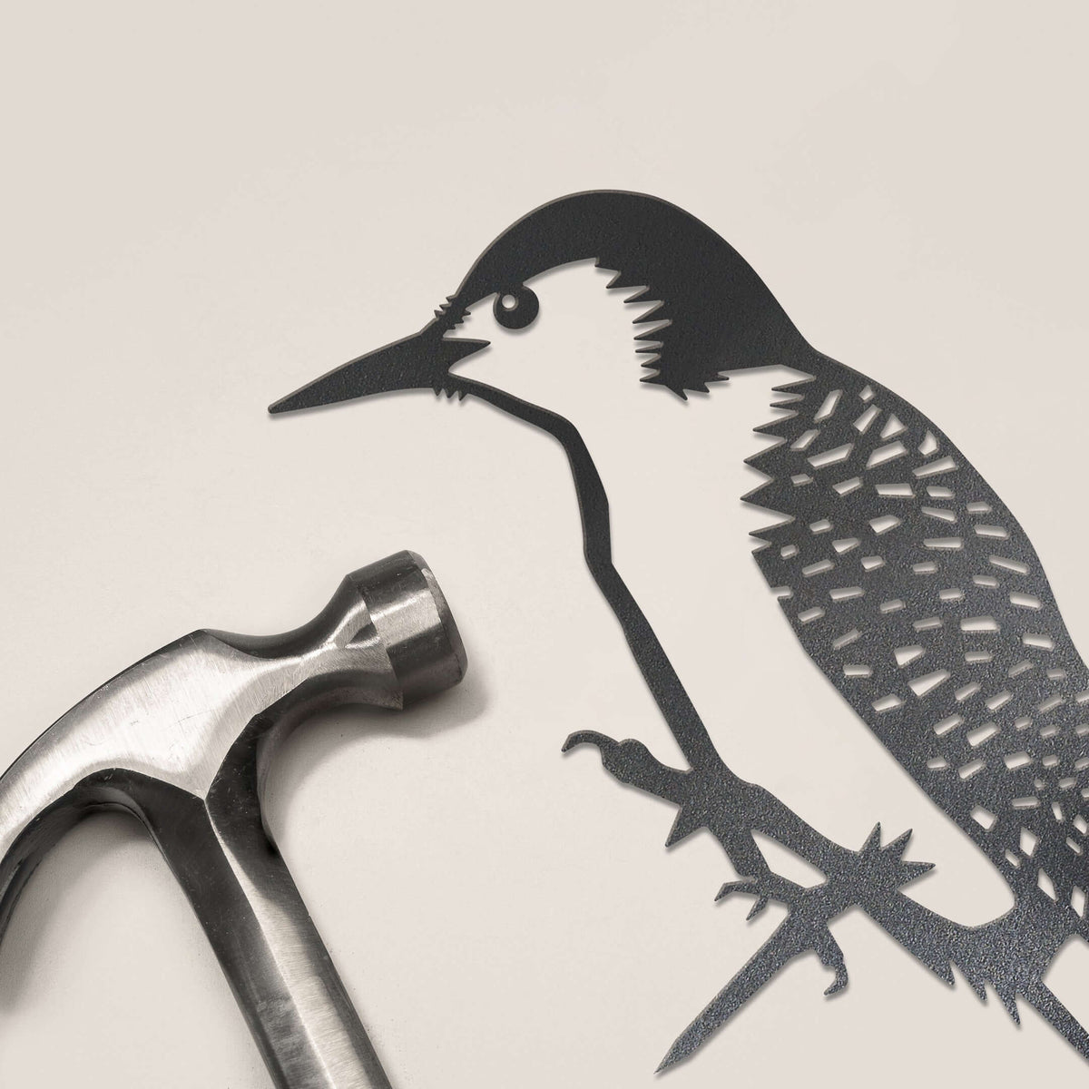 Woodpecker steel silhouette beside a hammer.