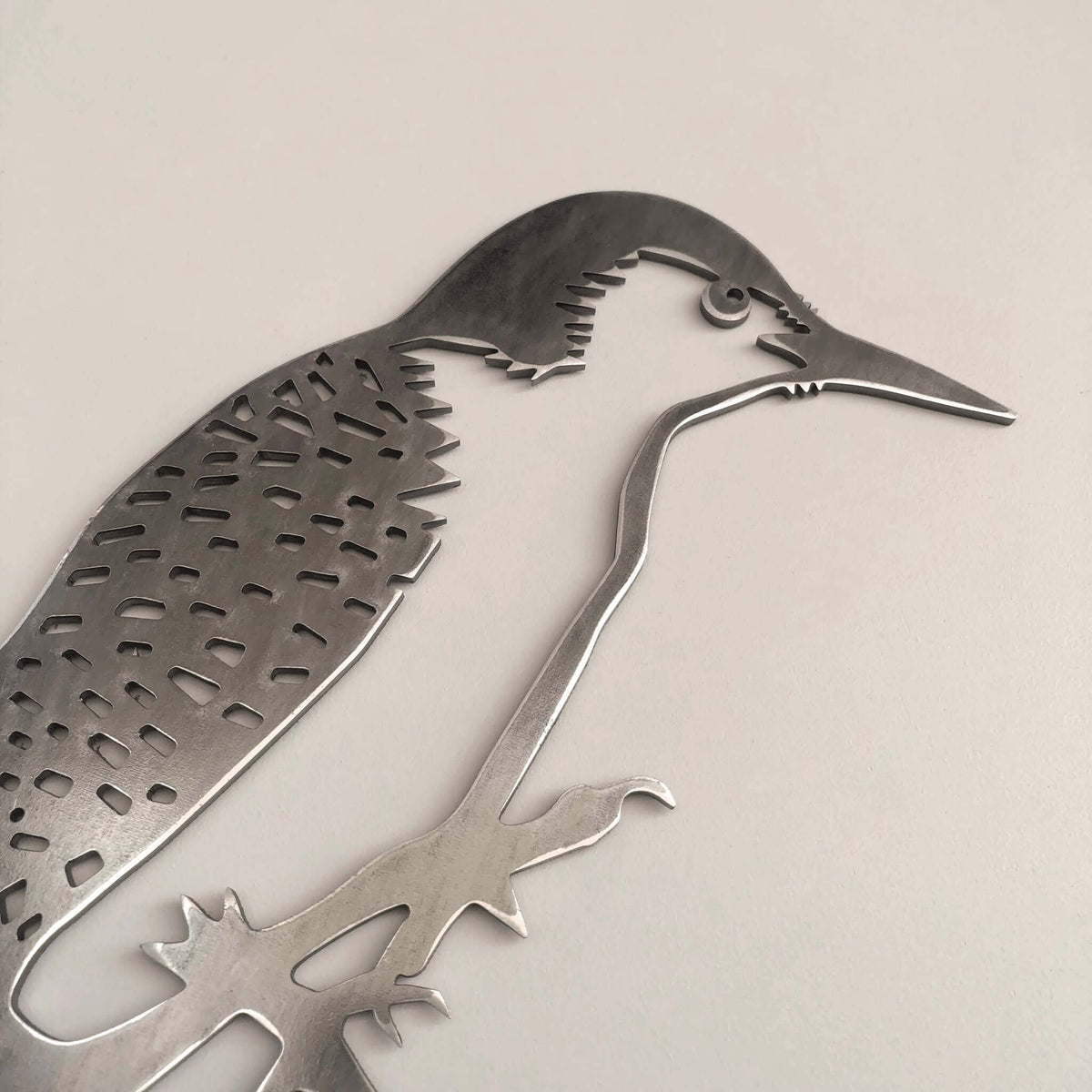 Close-up of the Woodpecker face, feather cutouts and claws in gray steel.