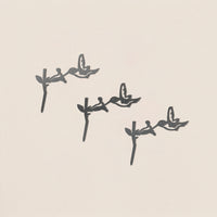 Three black hummingbird silhouettes hover near flowers, diagonally arranged on a light beige background. This minimalist design highlights the birds in mid-flight—perfect for the Baby Bird Bundle - Hummingbird Trio.