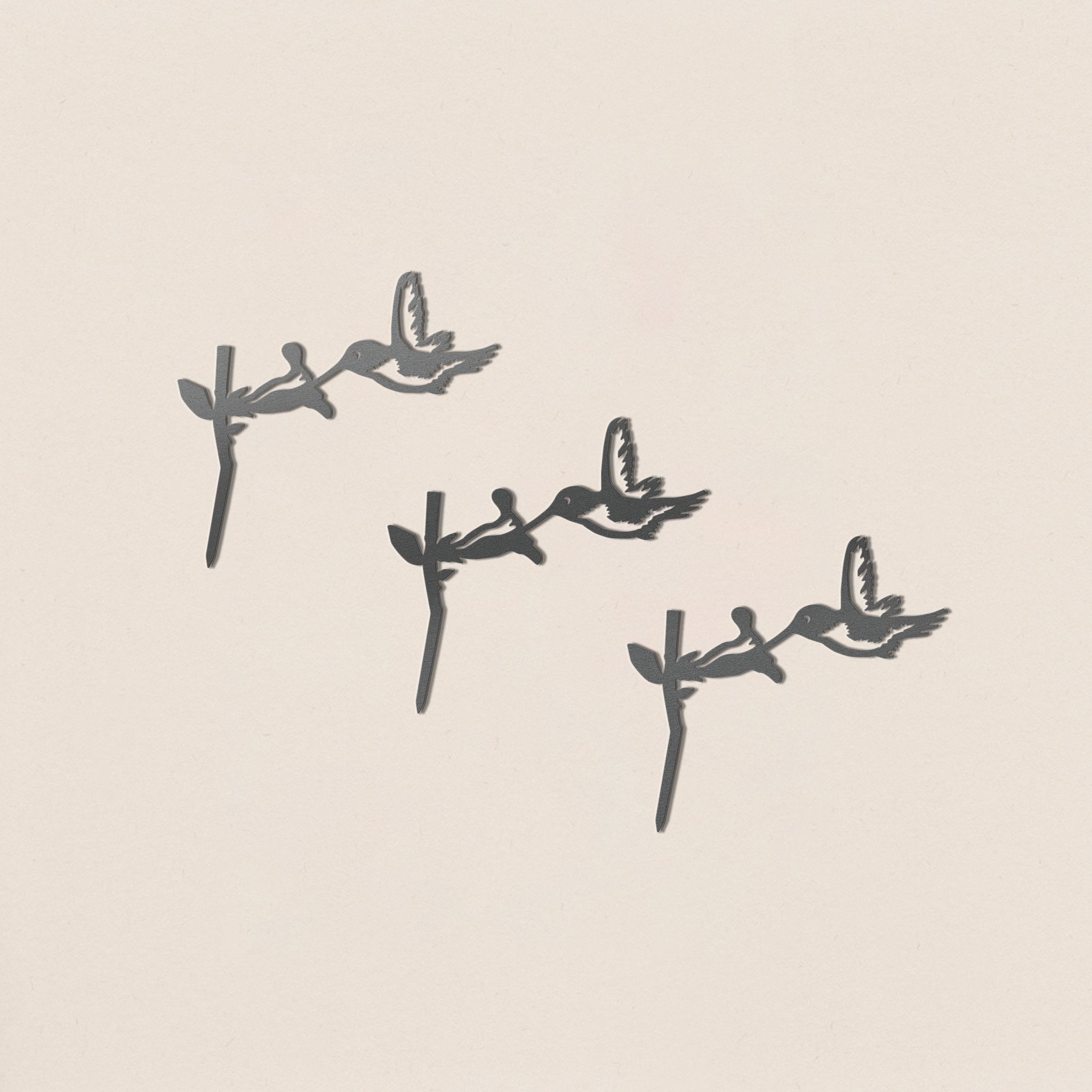 Three black hummingbird silhouettes hover near flowers, diagonally arranged on a light beige background. This minimalist design highlights the birds in mid-flight—perfect for the Baby Bird Bundle - Hummingbird Trio.