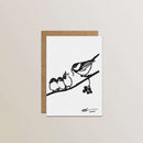 The Metalbird Greeting Card Set features a minimalist bird feeding two chicks on a berry branch, inspired by metal silhouette yard art, printed on a white card above a brown envelope.