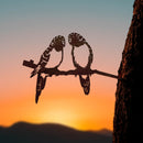 Parakeet Pair: Two Corten steel parakeets perched on a branch, attached to a tree trunk. A charming decor piece inspired by sunset and mountains—ideal as a unique bird gift or parrot lover decor.