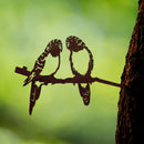 The Parakeet Pair is a metal silhouette of two Corten steel parakeets perched on a branch and attached to a tree trunk—a striking piece of parrot decor and an ideal bird-themed gift for nature lovers.