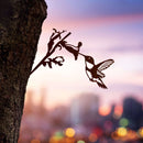 Corten steel Hummingbird sculpture tapping into a tree at sunset. Striking outdoor bird art. Perfect gift for bird lovers.